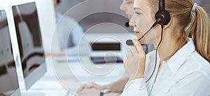 Call center. Group of casual dressed operators at work. Blond business woman in headset at customer service office