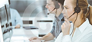 Call center. Group of casual dressed operators at work. Blond business woman in headset at customer service office