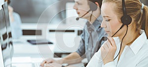 Call center. Group of casual dressed operators at work. Blond business woman in headset at customer service office