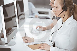 Call center. Group of casual dressed operators at work. Blond business woman in headset at customer service office