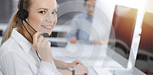 Call center. Group of casual dressed operators at work. Blond business woman in headset at customer service office