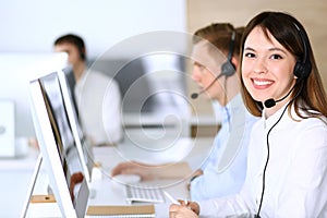 Call center. Group of diverse operators at work. Focus on beautiful asian woman in headset at customer service office