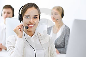 Call center. Group of operators at work. Focus on beautiful woman receptionist in headset at customer service white photo