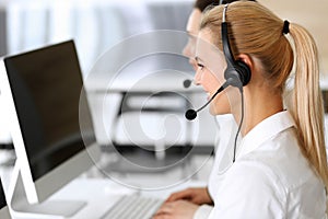 Call center. Happy and excited business woman using headset while consulting clients online. Customer service office or