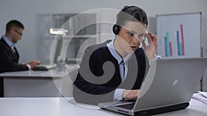 Call center manager in headset checking data on laptop, customer support