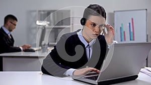 Call center manager in headset checking data on laptop, customer support