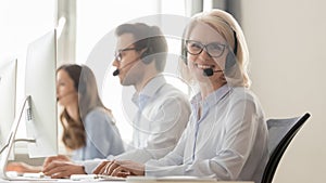 Call center mature employee sitting at workplace pose for camera