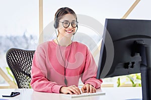 Call center operator businesswoman wearing headset and using computer while working from home