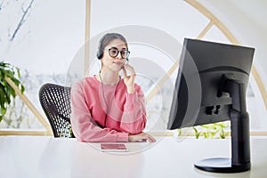 Call center operator businesswoman wearing headset and using computer while working from home