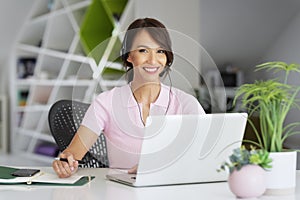 Call center operator businesswoman wearing headset and using laptop while working from home
