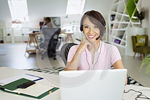 Call center operator businesswoman wearing headset and using laptop while working from home