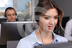 Call center operators working in modern office, focus on young woman with headset