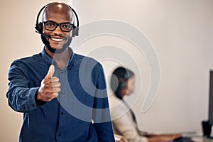 Call center, thumbs up and a man smile for customer service, crm or telemarketing support. Black person, consultant or