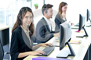 Call center worker accompanied by her team. Smiling customer support operator at work. Professional operator concept