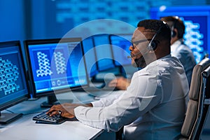 Call-center worker is speaking with the client by headset. Workplace of the african-american support operator.