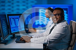 Call-center worker is speaking with the client by headset. Workplace of the african-american support operator.