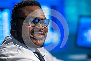 Call-center worker is speaking with the client by headset. Workplace of the african-american support operator.