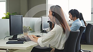 Call center young employee working with headset, Smiling customer support operator team at work surrounded