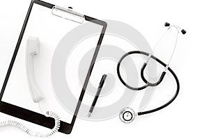 Call doctor. Phone, clip pad and stethoscope on white background top view