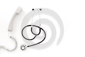 Call doctor. Phone and with stethoscope on white background top view copyspace