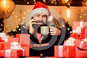 Call friends and family. happy new year. christmas time. bearded man santa hat. man drink hot milk. xmas present and