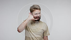 Call me! Positive handsome bearded man looking at camera playful winking flirting and holding telephone