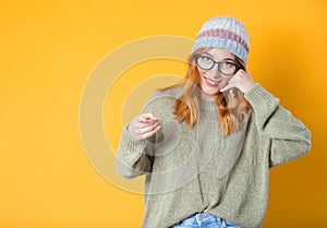 Call me. Woman gesturing at speaking on phone while looking to camera, isolated on yellow background. Woman on phone