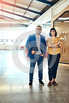 They call us the creative go-getters. Portrait of two designers standing together in an office.