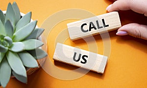 Call Us symbol. Wooden blocks with words Call Us. Beautiful green background with succulent plant. Businessman hand. Business and