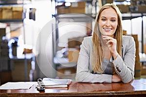 Call us for your import and export needs. Portrait of a young woman standing at a counter in a warehouse.