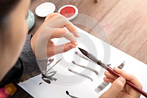 The calligrapher arranges the point of the brush with a brush in his hand