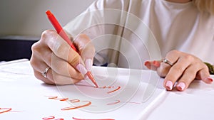 Calligrapher student practices in writing word LOVE with red marker on canvas. Creative artist freelancer working on