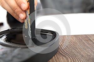 The calligrapher is studying ink on the inkstone with ink sticks in hand
