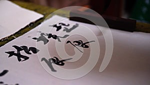 A calligrapher is writing Chinese calligraphy with black ink. Translation: Origin from Green Mountain Bamboo