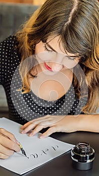 Calligrapher Young Woman writes phrase on white paper. Bible phrase about love Inscribing ornamental decorated letters