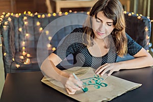 Calligrapher Young Woman writes phrase on white paper. Go green. Inscribing ornamental decorated letters. Calligraphy