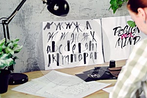 Calligraphic drawings with watercolor on the calligrapher`s desktop. Tools and works of the artist.