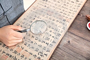 Calligraphy artists hold a magnifying glass to appreciate Wang Xizhi`s preface to Lanting