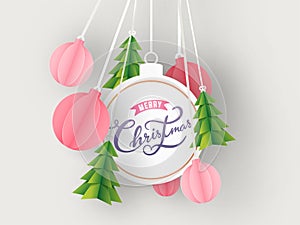 Calligraphy text Merry Christmas in bauble shape frame with hanging paper cut Xmas tree and ornament balls decorated on white