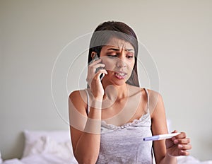 Calling on some assistance regarding her results. an attractive young woman taking a pregnancy test at home.