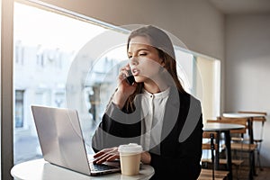 Calling you to inform about stage of work. Indoor shot of serious and focused successful businesswoman in trendy outfit