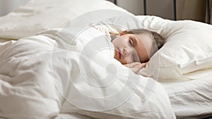 Sweet little kid girl having healthy day nap in bed photo