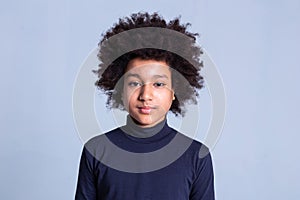 Calm African American boy with wild hairstyle posing on monochromic background