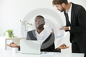 Calm african-american businessman practicing yoga at work ignori