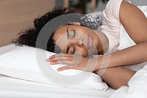 Calm african American girl sleeping on white soft pillow
