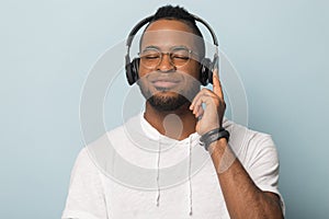 Calm African American man in headphones enjoying favorite music