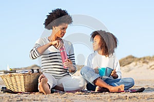 Calm African American mother and daughter on picnic on beach