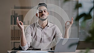 Calm arabian business man professional worker eyes closed taking break meditating on work desk ignoring stress breathing