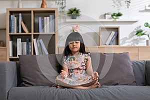 Calm of Asian child cute making yoga meditation with inhale and exhale. Sit on couch for focusing mind and soul. Relaxed with hand