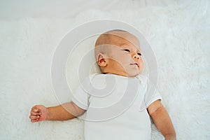 Calm Asian newborn baby lying on bed